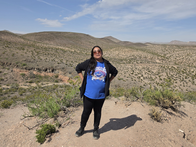 Laura Lara poses for a photo outdoors with rolling desert hills in the background.