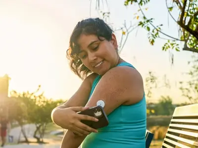A woman checks her cgm device, a continuous glucose monitor for blood sugar.