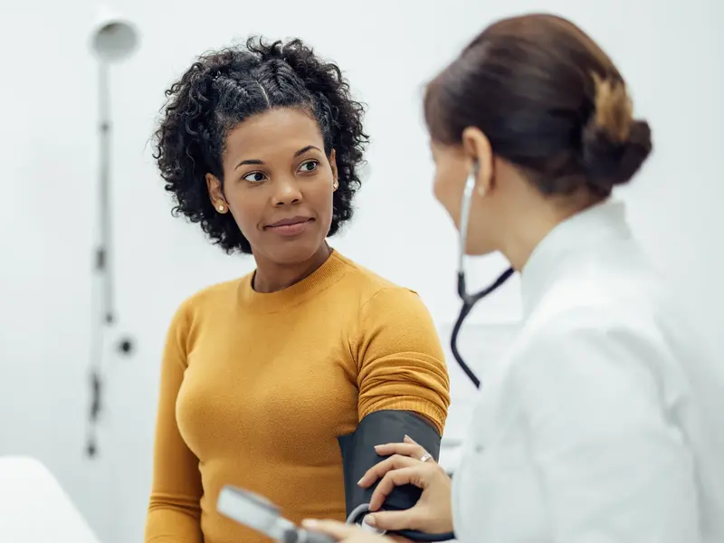 Doctor measuring blood pressure of a smiling woman